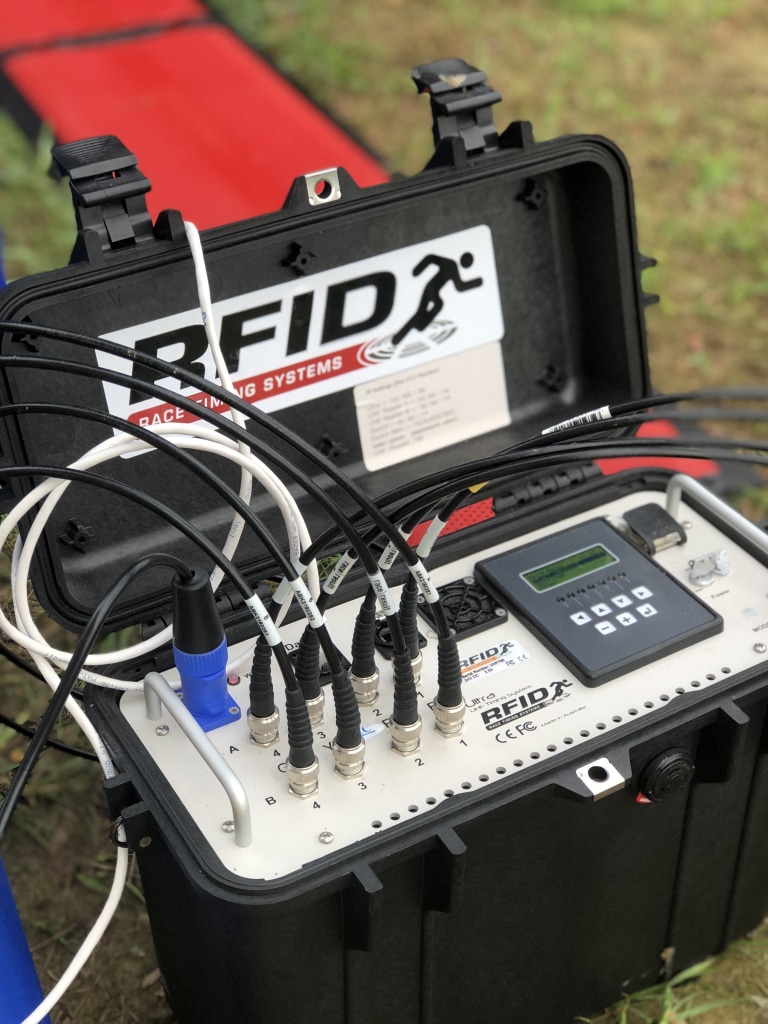 RFID timing reader in its case, cabled to red timing mats at a finish line